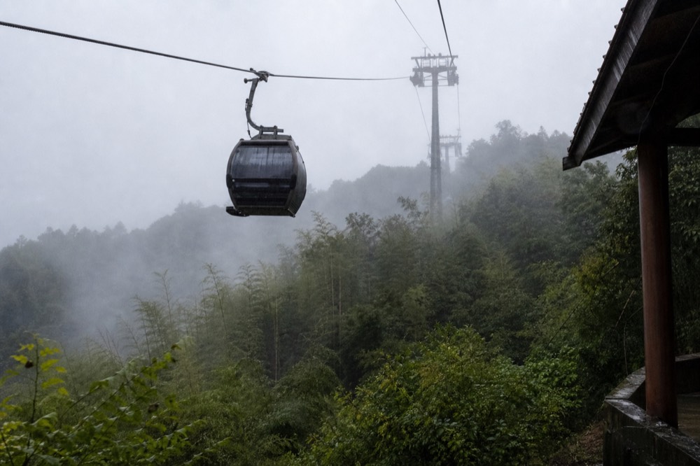 A gondola cabin seen from below against the sky above the Maokong hillside, no text, no logos, no people