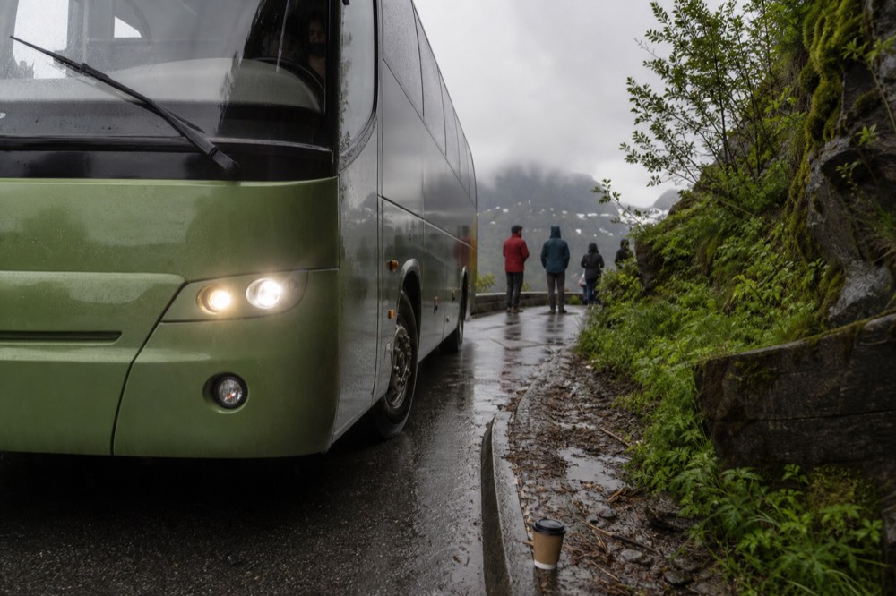 A green hillside shuttle bus waiting at a mountain road stop near Maokong, no text, no logos, no people