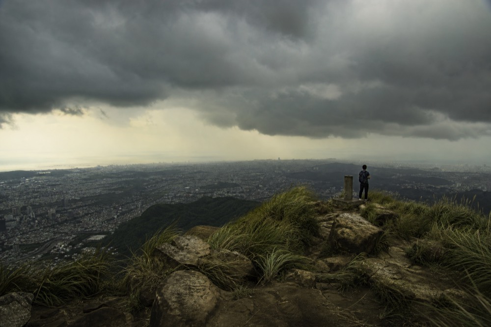 Dark typhoon clouds rolling over the Taipei basin seen from a mountain ridge, no text, no logos, no people